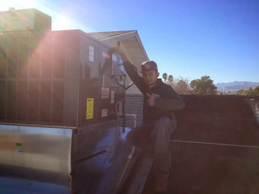 HVAC technician performing AC Tune-Up on a rooftop unit in New Brighton